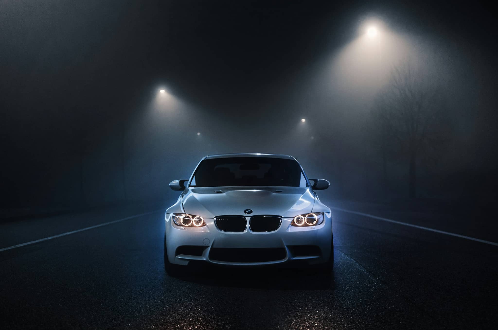 BMW M3 z włączonymi reflektorami na ciemnej, zamglonej drodze