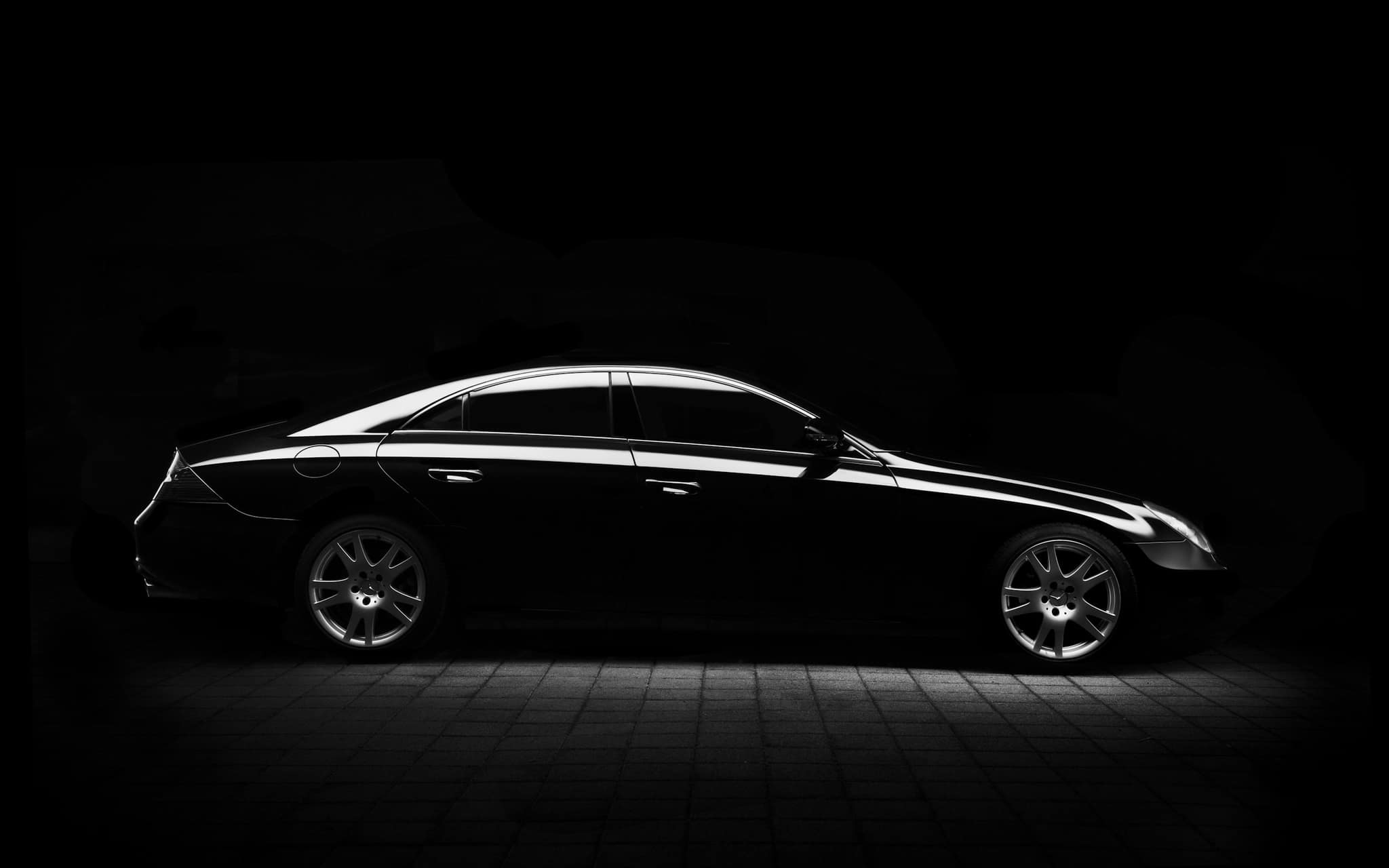 Czarny Mercedes CLS w ciemnym studiu detailingowym, światło krawędziowe podkreśla linie lakieru